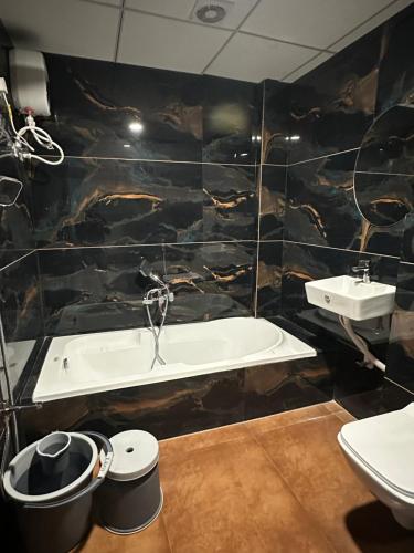 a bathroom with a sink and a tub and a toilet at Hotel victoria prime in Surat