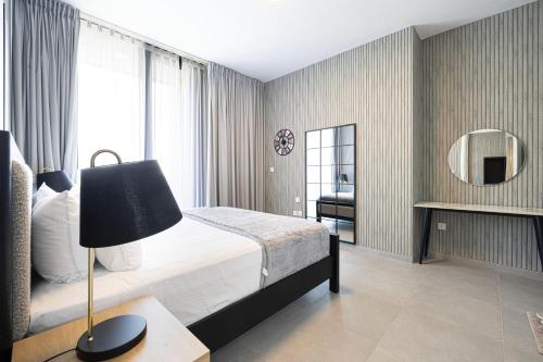 a bedroom with a bed and a lamp and a mirror at 1BR The Modern Al Jada Home by Blue Cloud Holidays in Sharjah