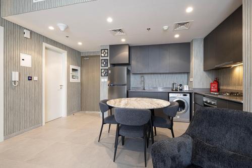 a kitchen with a table and chairs in a room at 1BR The Modern Al Jada Home by Blue Cloud Holidays in Sharjah