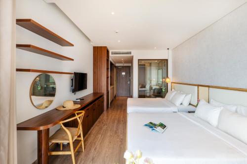 a hotel room with two beds and a desk at Apec Mandala Harmony Resort & Spa in Mui Ne