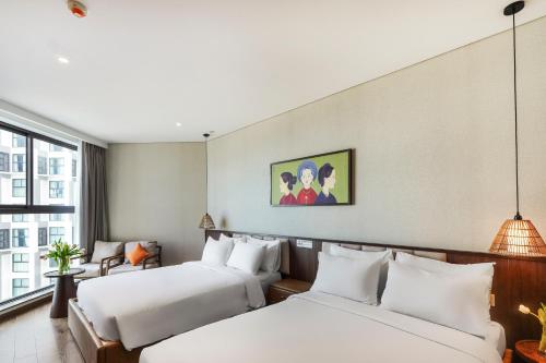 a hotel room with two beds and a window at Apec Mandala Harmony Resort & Spa in Mui Ne