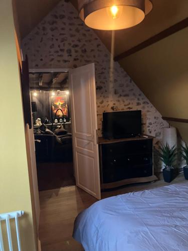 une chambre avec un lit et une télévision à écran plat dans l'établissement La Fontaine du Perche - Piscine Spa Sauna Home cinema, à La Livarderie