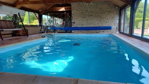 une grande piscine avec de l'eau bleue dans l'établissement La Fontaine du Perche - Piscine Spa Sauna Home cinema, à La Livarderie
