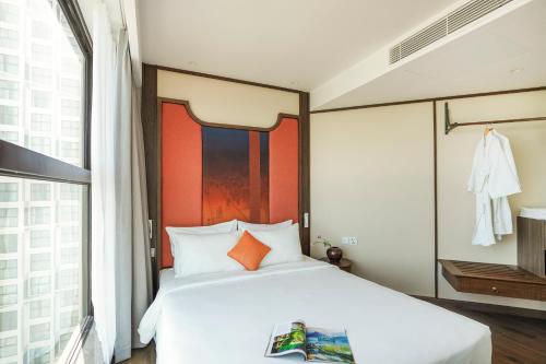 a bedroom with a large white bed and a window at Apec Mandala Harmony Resort & Spa in Mui Ne
