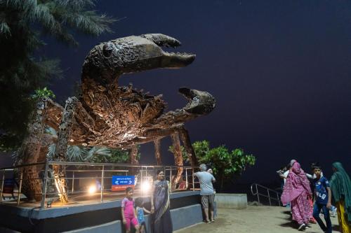 a group of people standing in front of a dinosaur statue at Aarya Inn in Srīvardhan