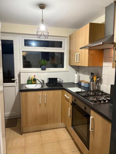 a kitchen with wooden cabinets and a sink and a window at Mayfield House in Hull