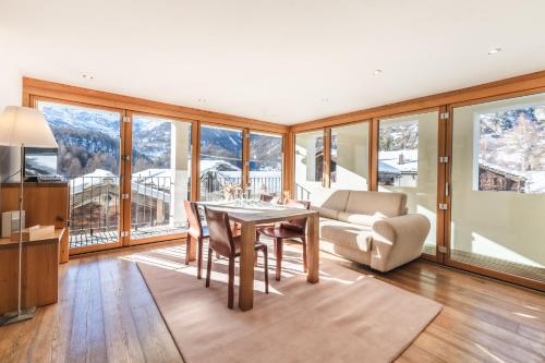 a living room with a table and chairs and mountains at Sonnmatten Boutique Hotel & Apartments Zermatt in Zermatt