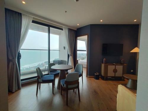 a living room with a table and chairs and a large window at Apec Mandala Harmony Resort & Spa in Mui Ne