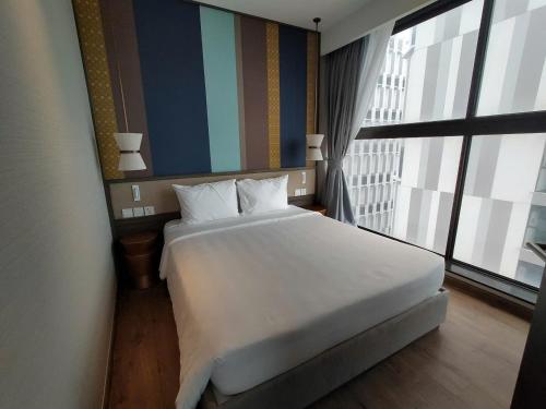 a bedroom with a large white bed and a large window at Apec Mandala Harmony Resort & Spa in Mui Ne