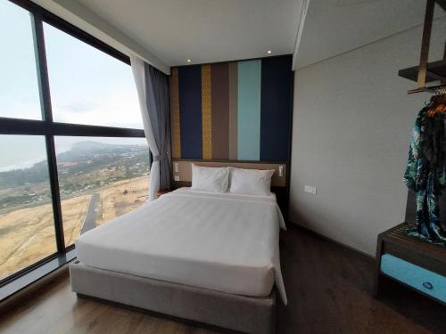 a bedroom with a large bed with a large window at Apec Mandala Harmony Resort & Spa in Mui Ne
