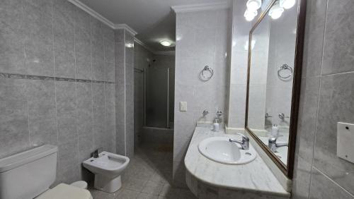 a white bathroom with a sink and a toilet at Tajy Iguazu Hotel in Puerto Iguazú