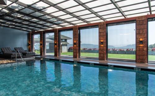 a swimming pool in a building with windows at Brightland Resort & Spa in Mahabaleshwar