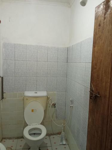 a bathroom with a toilet and a tiled wall at Hideout 2 in Ukunda