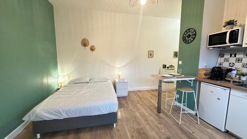 a bedroom with a bed and a desk and a kitchen at Le petit Verdier Mosellan - Thionville - 2P in Thionville