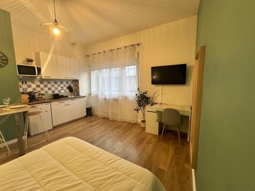 a bedroom with a bed and a desk and a kitchen at Le petit Verdier Mosellan - Thionville - 2P in Thionville