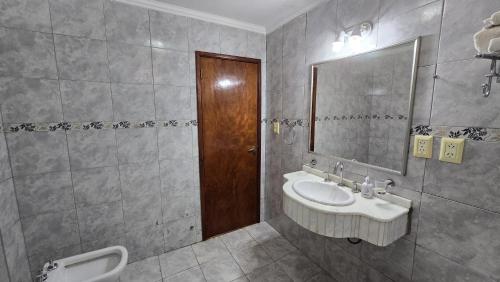 a bathroom with a sink and a mirror and a urinal at Tajy Iguazu Hotel in Puerto Iguazú