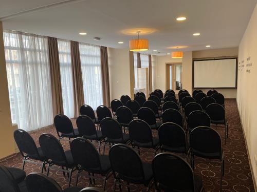a conference room with chairs and a white screen at Hotel Monogram Park in Ruma