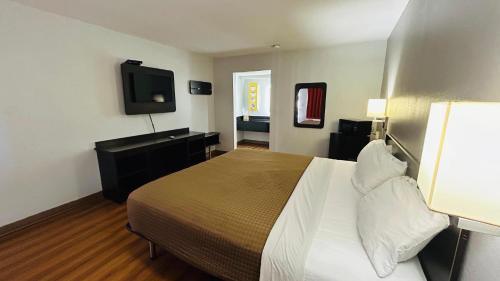 a hotel room with a bed and a flat screen tv at Super 7 Inn Tupelo in Tupelo