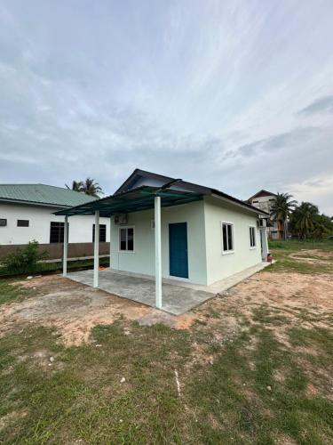 a small white house with a blue roof at Teratak Manis Homestay in Kuantan