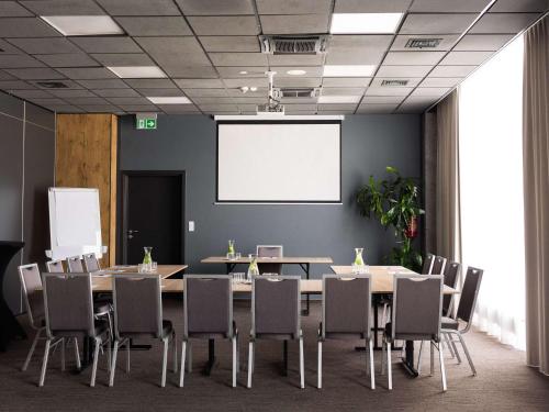 a conference room with a table and chairs and a whiteboard at Ibis Poznan Polnoc in Suchy Las
