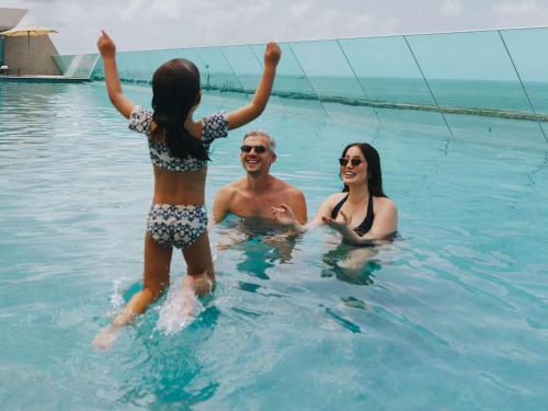a group of three people in the water at Novotel Recife Marina in Recife