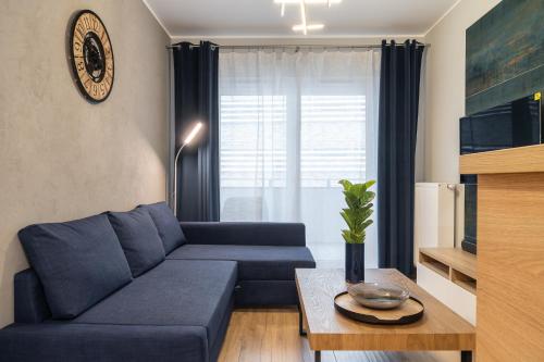 a living room with a blue couch and a table at RentPlanet - Kępa Mieszczańska in Wrocław