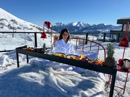 a woman sitting at a table in the snow at Gudauri Loft Hotel in Gudauri