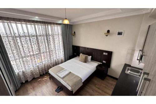 a bedroom with a bed and a large window at Hemak Suites Hotel in Nairobi