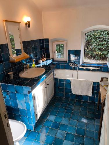 La salle de bains est pourvue de carrelage bleu, d'une baignoire et d'un lavabo. dans l'établissement Maison Robert, à La Tour-dʼAigues