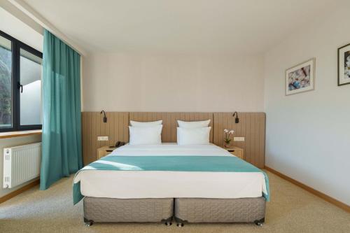 a bedroom with a large bed with green curtains at Apricot Aghveran Resort in Agveran