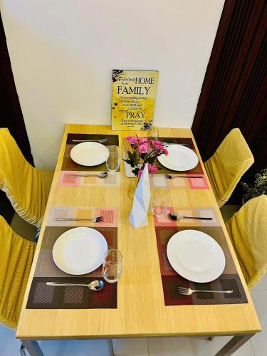 a wooden table with white plates and flowers on it at ALG's Place Quezon City in Manila