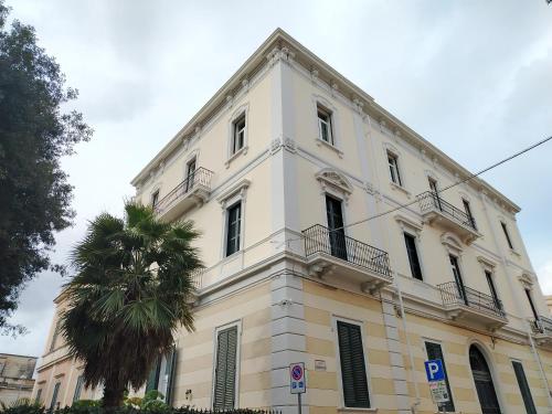 a white building with a palm tree in front of it at Palazzo Castellano in Lecce