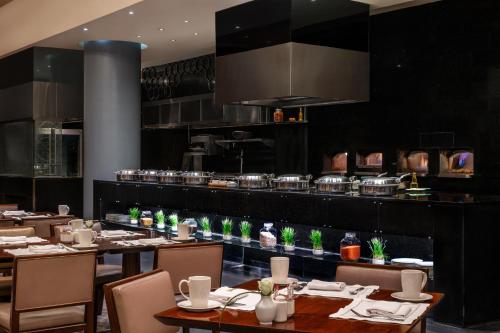 a restaurant with tables and chairs and a kitchen at Sofitel Cairo Downtown Nile in Cairo