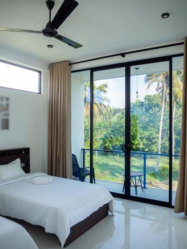 a bedroom with a bed and a large window at Mates Villa in Weligama