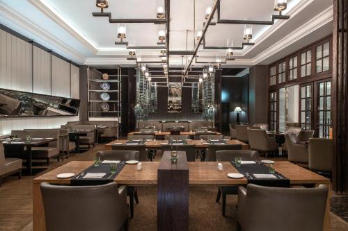 a restaurant with wooden tables and chairs and a chandelier at Sofitel Cairo Downtown Nile in Cairo