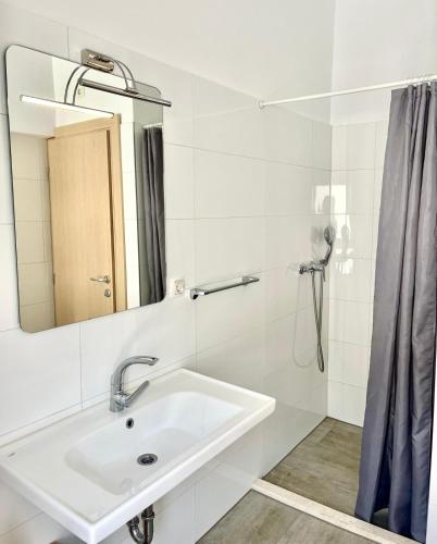 ein weißes Badezimmer mit Waschbecken und Spiegel in der Unterkunft Apartments ZINA in Lokva Rogoznica