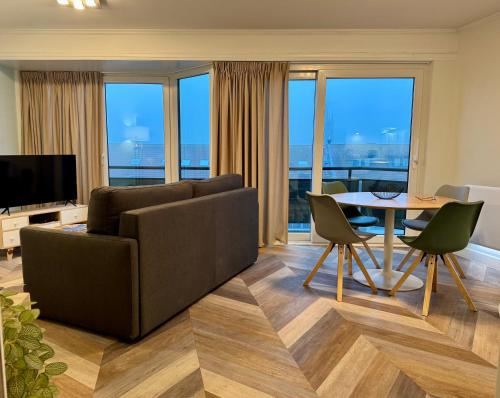 ein Wohnzimmer mit einer Couch und einem Tisch mit Stühlen in der Unterkunft Cozy Panorama Flat by the Beach in Knokke-Heist