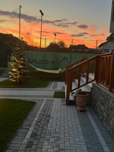 a sunset over a brick walkway with a hammock at Pensiunea Magic in Băile Govora