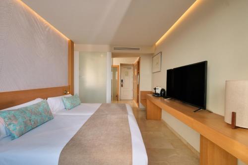 a hotel room with a bed and a flat screen tv at Hotel Son Caliu Spa Oasis in Palmanova