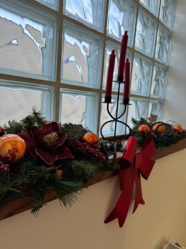 a christmas wreath on a window ledge with two candles at Pensiunea Magic in Băile Govora
