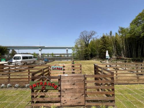 a wooden fence in a field with a bridge in the background at NTV Smoky Garden in Owariasahi
