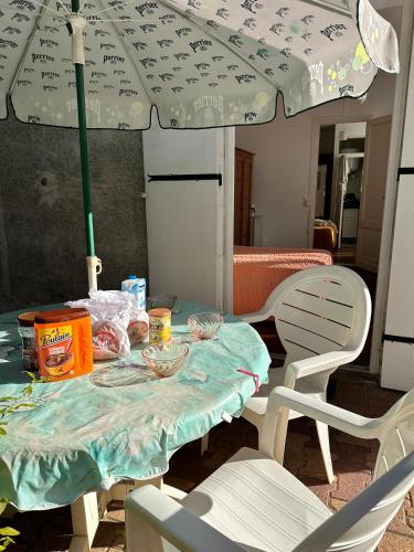 - une table avec un parasol et une table avec des chaises dans l'établissement 2 chambres Arcachon & Moulleau accès Plage - Salle de bain & coin petit déjeuner, à Arcachon