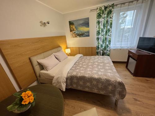 a hotel room with a bed and a television at Willa Bursztyn in Dębki