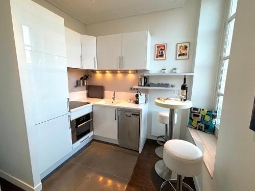 une petite cuisine avec des armoires blanches et une table dans l'établissement L'appartement des Archives, à Paris