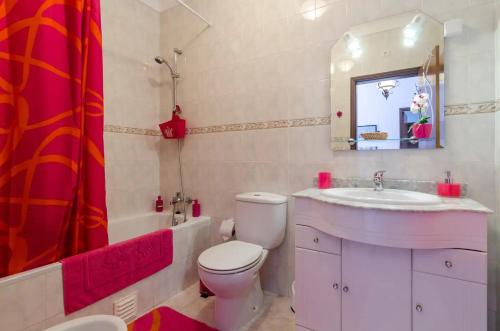 ein Badezimmer mit Toilette, Waschbecken und Spiegel in der Unterkunft Villa Figueira in Portimão
