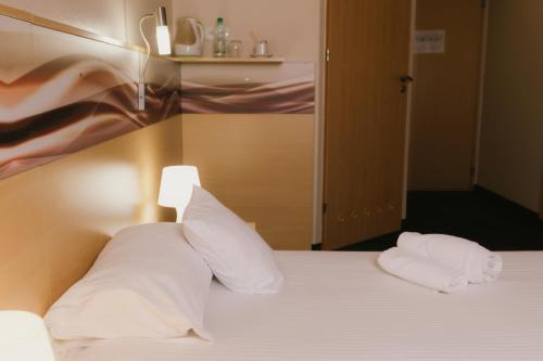 a bedroom with a bed with white pillows at Quality Silesian Hotel in Katowice