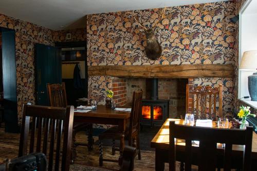 una sala da pranzo con tavolo e camino di The Stag and Huntsman at Hambleden a Henley on Thames