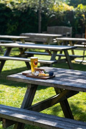 a picnic table with a plate of food and a drink on it at The Stag and Huntsman at Hambleden in Henley on Thames