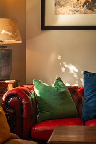 a living room with a red couch with a green pillow at The Stag and Huntsman at Hambleden in Henley on Thames