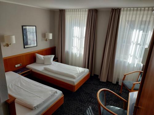 a hotel room with two beds and a chair at Hotel-Restaurant Roter Ochsen in Lauchheim